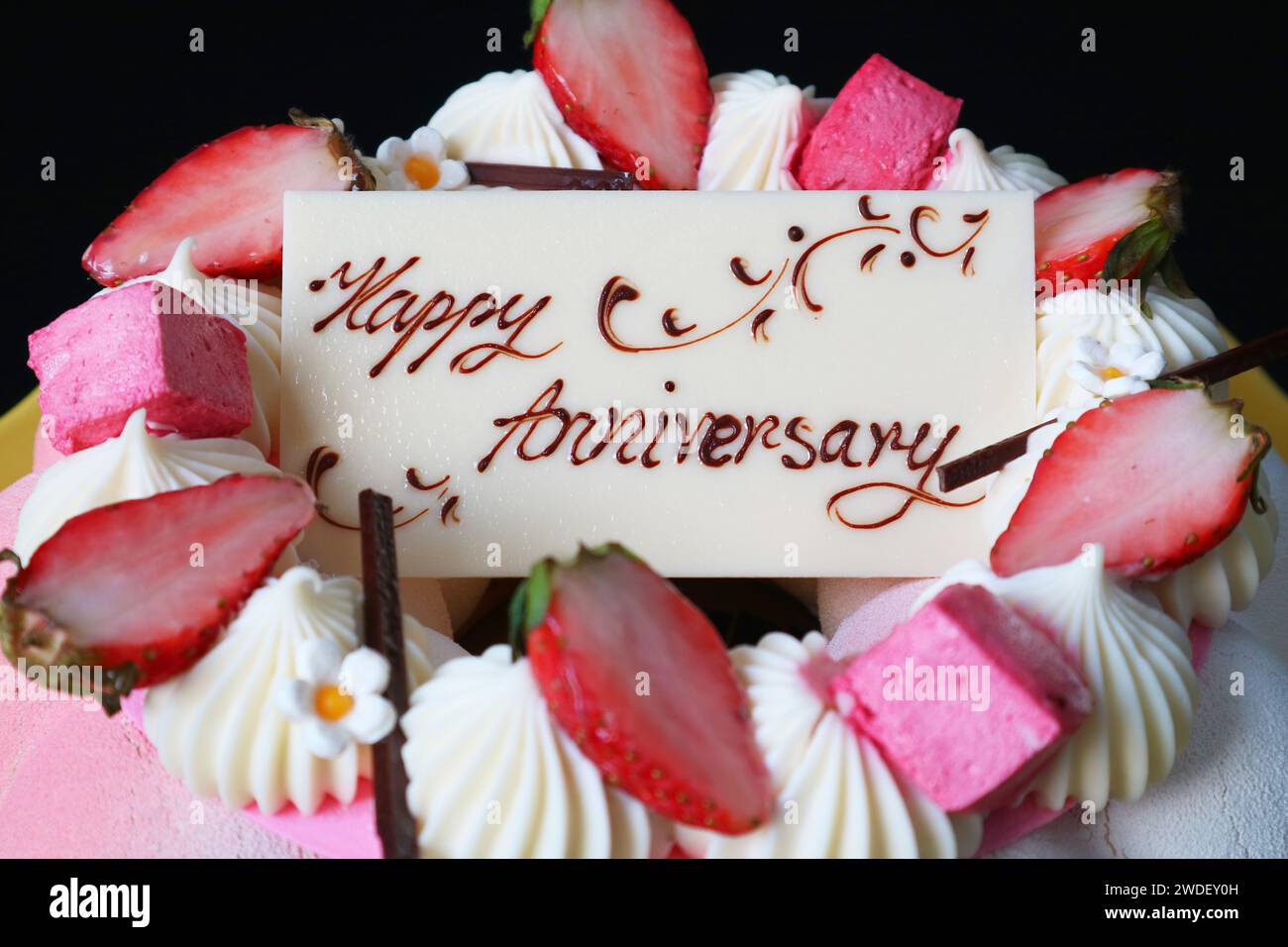 Primo piano del biglietto d'auguri per l'anniversario del cioccolato bianco sulla torta alla mousse di fragole Foto Stock