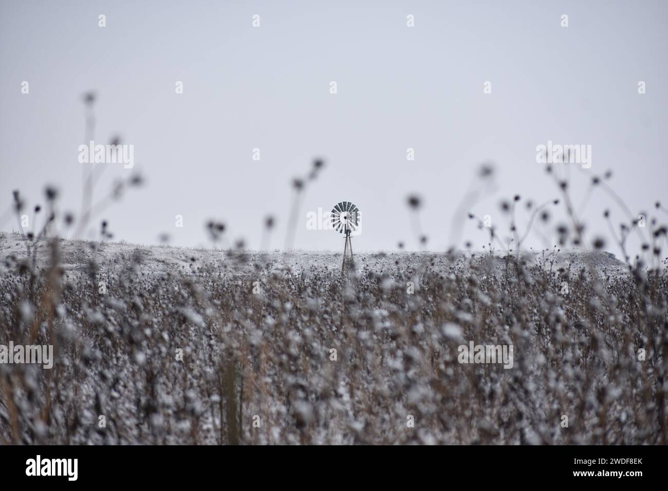 Un mulino a vento d'epoca è raffigurato da solo in un desolato paesaggio invernale Foto Stock