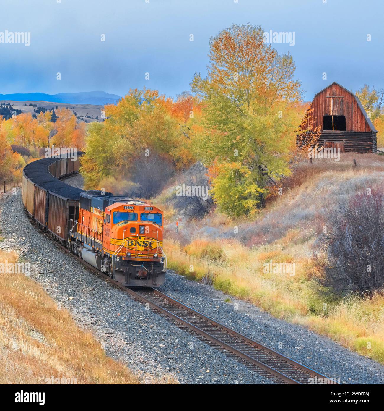 treno che passa da un vecchio fienile in autunno a jens, montana Foto Stock