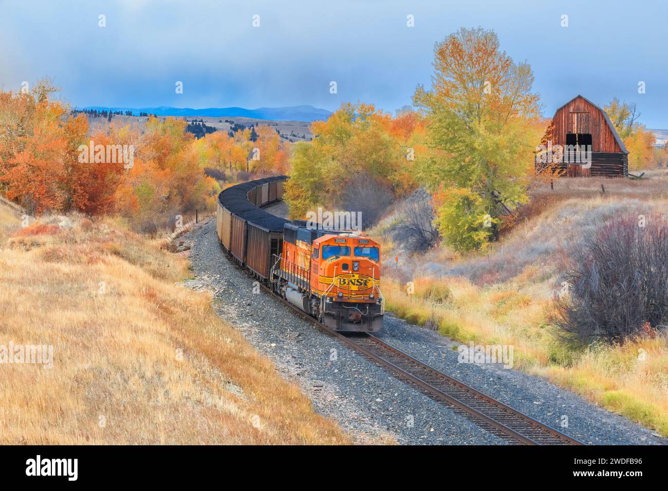 treno che passa da un vecchio fienile in autunno a jens, montana Foto Stock