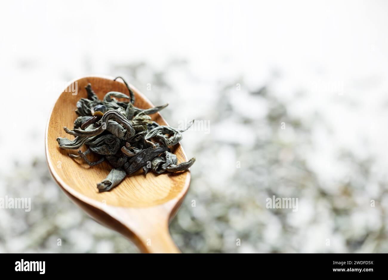 foglie di tè verde in cucchiaio di legno Foto Stock
