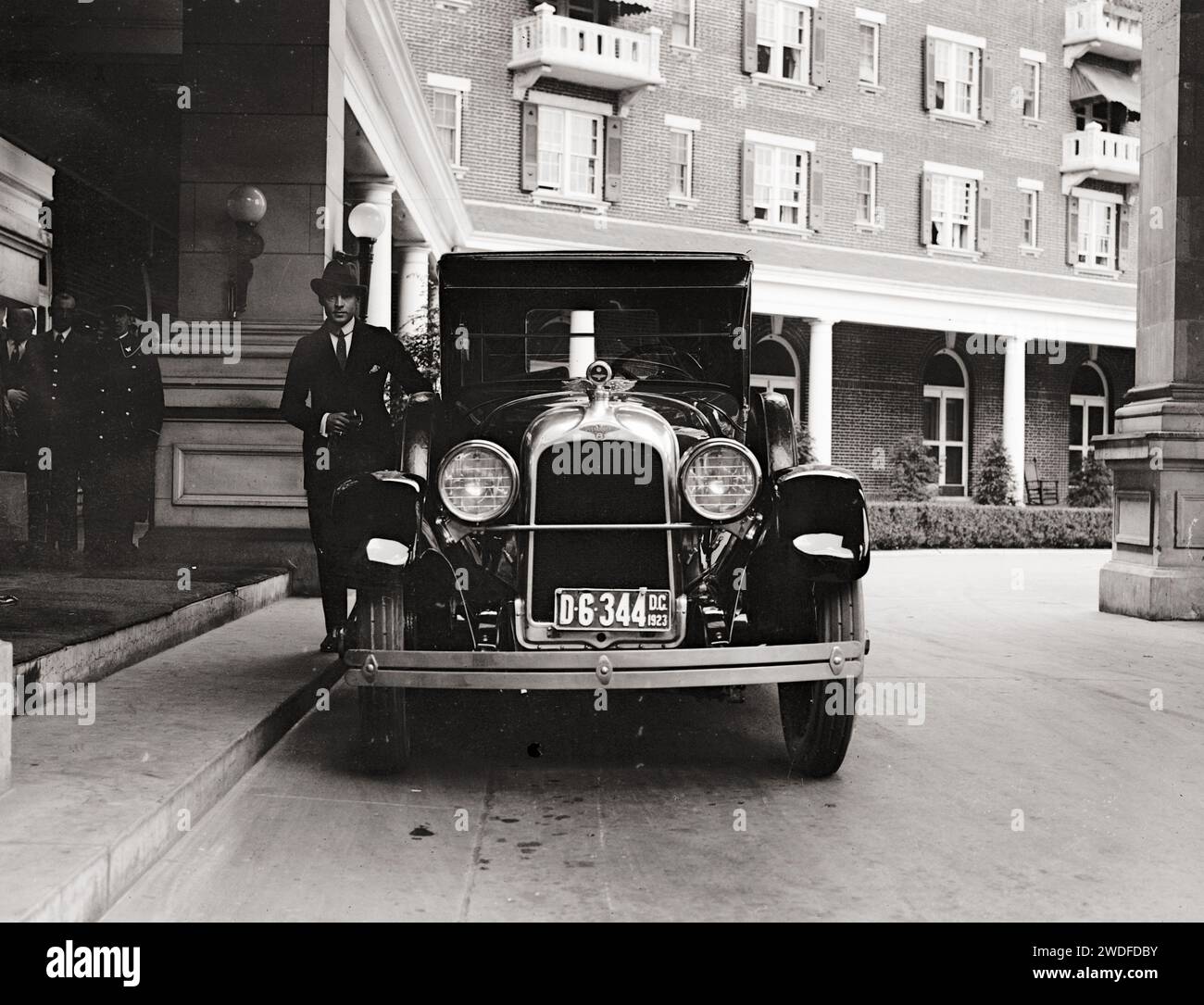 Rodolfo Valentino 1923 in piedi accanto a una bella auto d'epoca all'ingresso dell'hotel Foto Stock