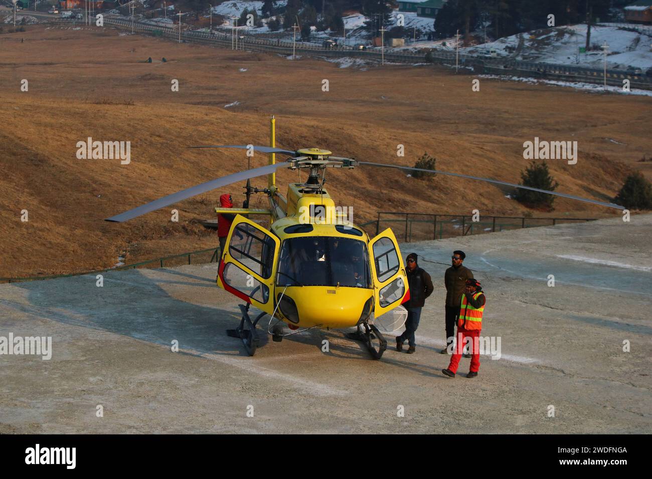 Srinagar Kashmir, India. 20 gennaio 2024. La gente si trova accanto a un elicottero a Gulmarg, a circa 55 km da Srinagar. Il prolungato periodo di secchezza di quest'inverno nella valle del Kashmir ha inferto un duro colpo alla famosa stazione sciistica di Gulmarg. Le piste da sci, un tempo trafficate, sono ormai senza neve e sono motivo di delusione per i turisti e in particolare per gli appassionati di sci. L'assenza di nevicate stagionali ha comportato la cancellazione delle prenotazioni di massa per i proprietari di hotel, con un grave impatto sulle loro attività. Questa battuta d’arresto imprevista sottolinea la vulnerabilità delle economie dipendenti dall’inverno e l’urgente necessità di farlo Foto Stock