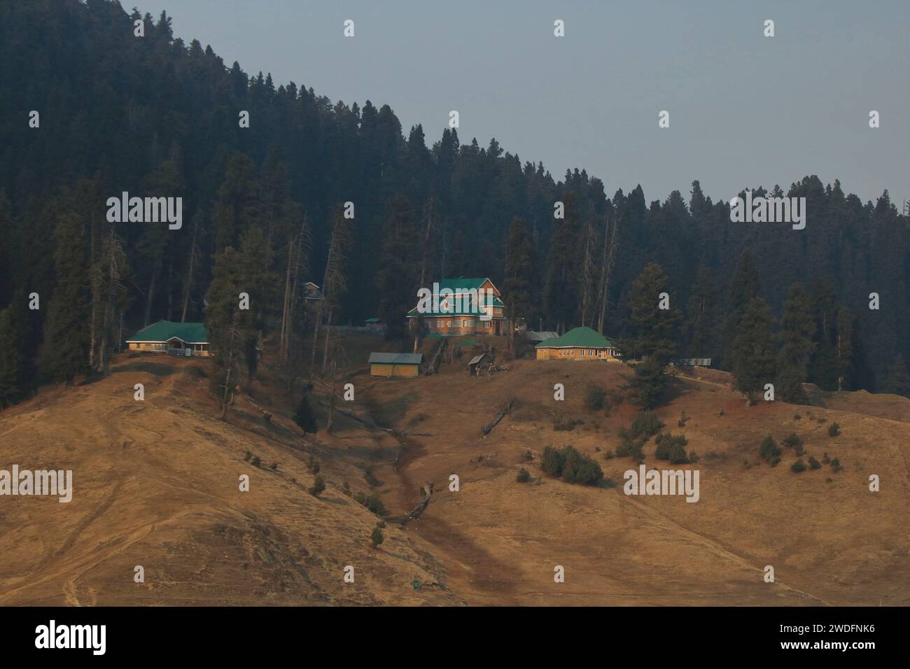 Srinagar Kashmir, India. 20 gennaio 2024. Vista sulle stazioni sciistiche e sulle piste da sci di Gulmarg, a circa 55 km da Srinagar. Il prolungato periodo di secchezza di quest'inverno nella valle del Kashmir ha inferto un duro colpo alla famosa stazione sciistica di Gulmarg. Le piste da sci, un tempo trafficate, sono ormai senza neve e sono motivo di delusione per i turisti e in particolare per gli appassionati di sci. L'assenza di nevicate stagionali ha comportato la cancellazione delle prenotazioni di massa per i proprietari di hotel, con un grave impatto sulle loro attività. Questa battuta d'arresto imprevista sottolinea la vulnerabilità delle economie dipendenti dall'inverno e l'urgente necessità f Foto Stock