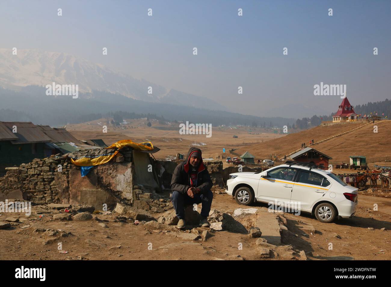 20 gennaio 2024, Srinagar Kashmir, India: Ashiq Hussain, una guida riposa a Gulmarg, a circa 55 km da Srinagar. Il prolungato periodo di secchezza di quest'inverno nella valle del Kashmir ha inferto un duro colpo alla famosa stazione sciistica di Gulmarg. Le piste da sci, un tempo trafficate, sono ormai senza neve e sono motivo di delusione per i turisti e in particolare per gli appassionati di sci. L'assenza di nevicate stagionali ha comportato la cancellazione delle prenotazioni di massa per i proprietari di hotel, con un grave impatto sulle loro attività. Questa battuta d’arresto imprevista sottolinea la vulnerabilità delle economie dipendenti dall’inverno e l’urgente necessità di stra Foto Stock