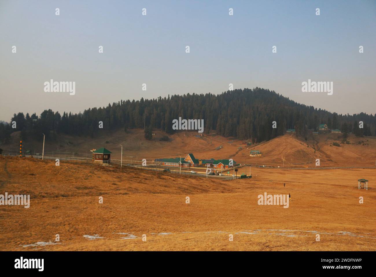 Srinagar Kashmir, India. 20 gennaio 2024. Vista sulle piste da sci di Gulmarg, a circa 55 km da Srinagar. Il prolungato periodo di secchezza di quest'inverno nella valle del Kashmir ha inferto un duro colpo alla famosa stazione sciistica di Gulmarg. Le piste da sci, un tempo trafficate, sono ormai senza neve e sono motivo di delusione per i turisti e in particolare per gli appassionati di sci. L'assenza di nevicate stagionali ha comportato la cancellazione delle prenotazioni di massa per i proprietari di hotel, con un grave impatto sulle loro attività. Questa battuta d’arresto imprevista sottolinea la vulnerabilità delle economie dipendenti dall’inverno e l’urgente necessità di strategie Foto Stock