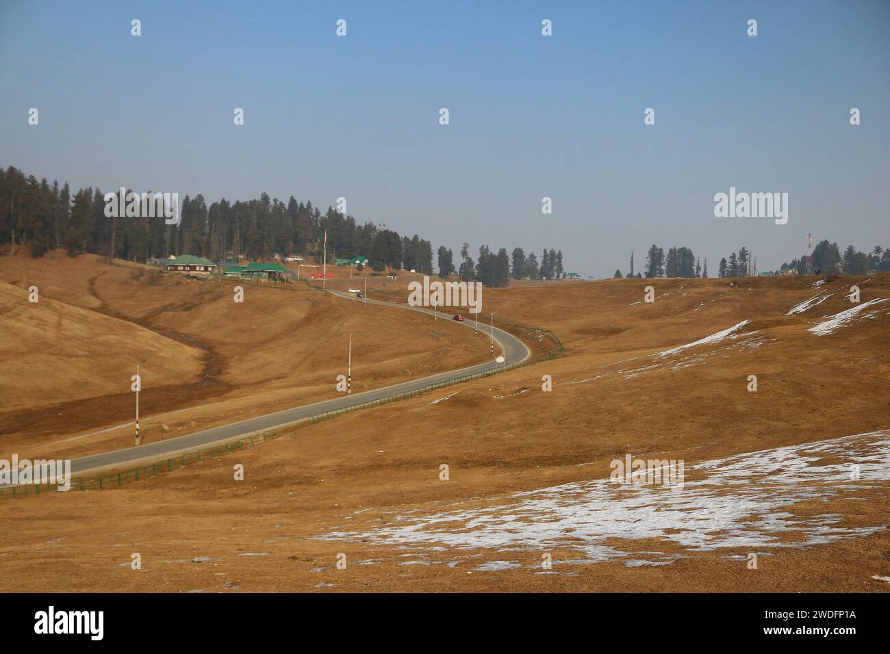 20 gennaio 2024, Srinagar Kashmir, India: Un veicolo si muove lungo una strada a Gulmarg, a circa 55 km da Srinagar. Il prolungato periodo di secchezza di quest'inverno nella valle del Kashmir ha inferto un duro colpo alla famosa stazione sciistica di Gulmarg. Le piste da sci, un tempo trafficate, sono ormai senza neve e sono motivo di delusione per i turisti e in particolare per gli appassionati di sci. L'assenza di nevicate stagionali ha comportato la cancellazione delle prenotazioni di massa per i proprietari di hotel, con un grave impatto sulle loro attività. Questa battuta d’arresto imprevista sottolinea la vulnerabilità delle economie dipendenti dall’inverno e l’urgente necessità di STR Foto Stock