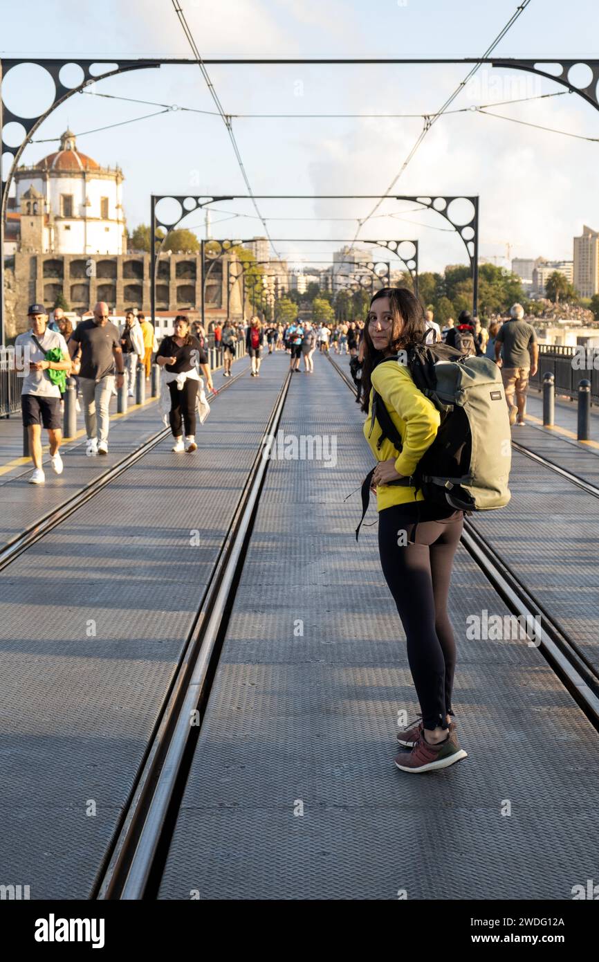 Porto, Portogallo - 17 settembre 2023. Giovane donna viaggiatrice e pedoni sul Ponte D. Luis I.. Fiume Douro e tetti in terracotta, patrimonio mondiale dell'UNESCO Foto Stock