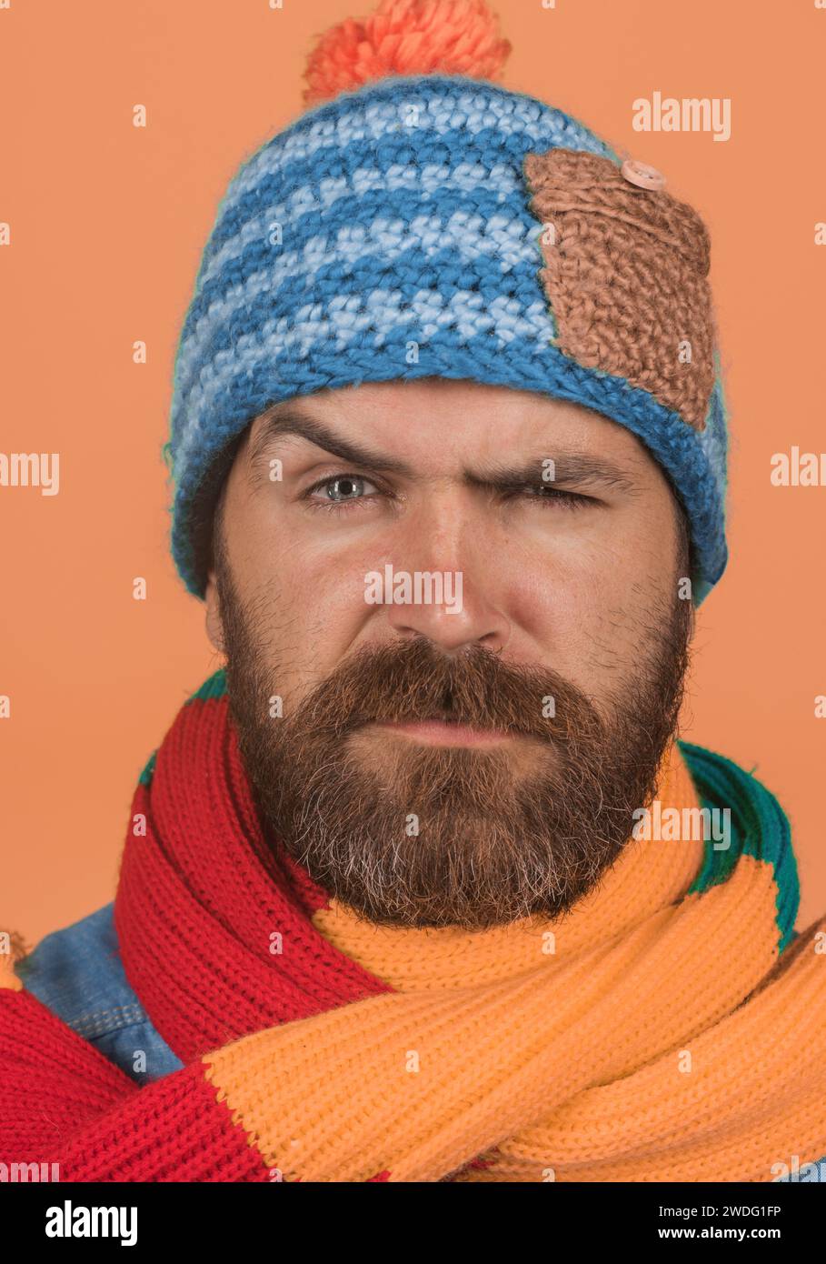 Abbigliamento autunno-inverno. Ritratto di primo piano uomo serio attraente con barba e baffi in cappello e sciarpa lavorati a maglia colorata. Moda autunno-inverno maschile Foto Stock