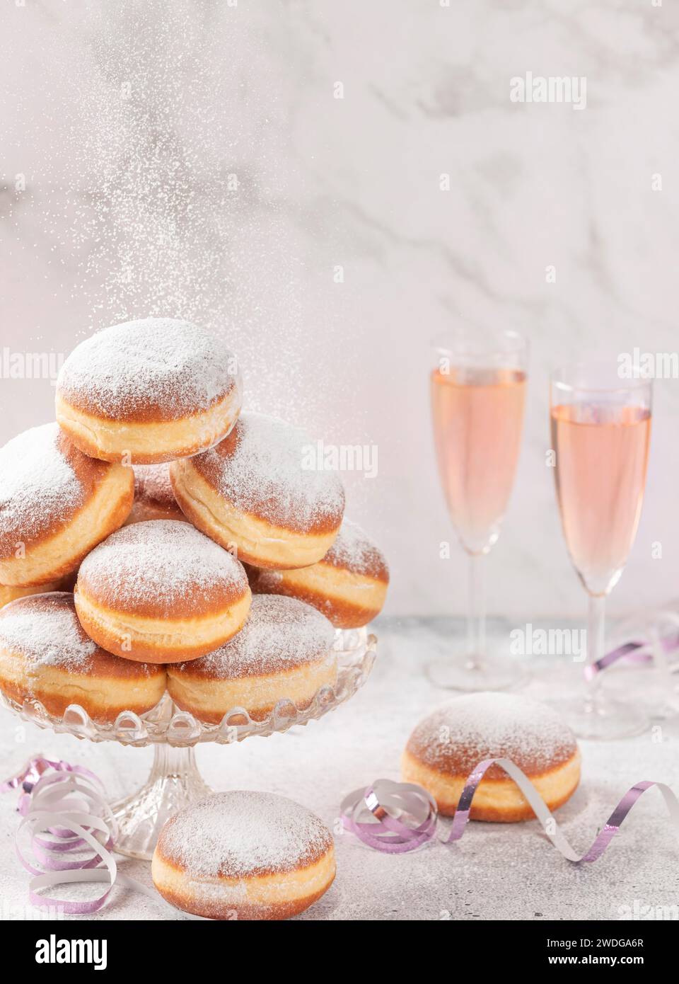 Gli impasti su un supporto di vetro con spumante rosa sullo sfondo e zucchero a velo Foto Stock