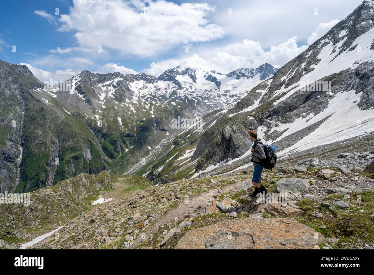 Alpinista sul sentiero escursionistico, vista sulla valle Floitengrund con la vetta del monte Greizer Spitze con la neve, discesa dal Noerdliche Foto Stock