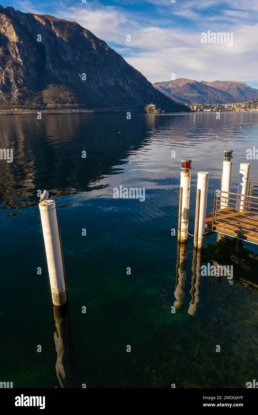 Molo sul Lago di Lugano con montagna e luce solare contro il cielo azzurro e la città di Lugano in Ticino, Svizzera, da campione d'Italia, Lombardia Foto Stock