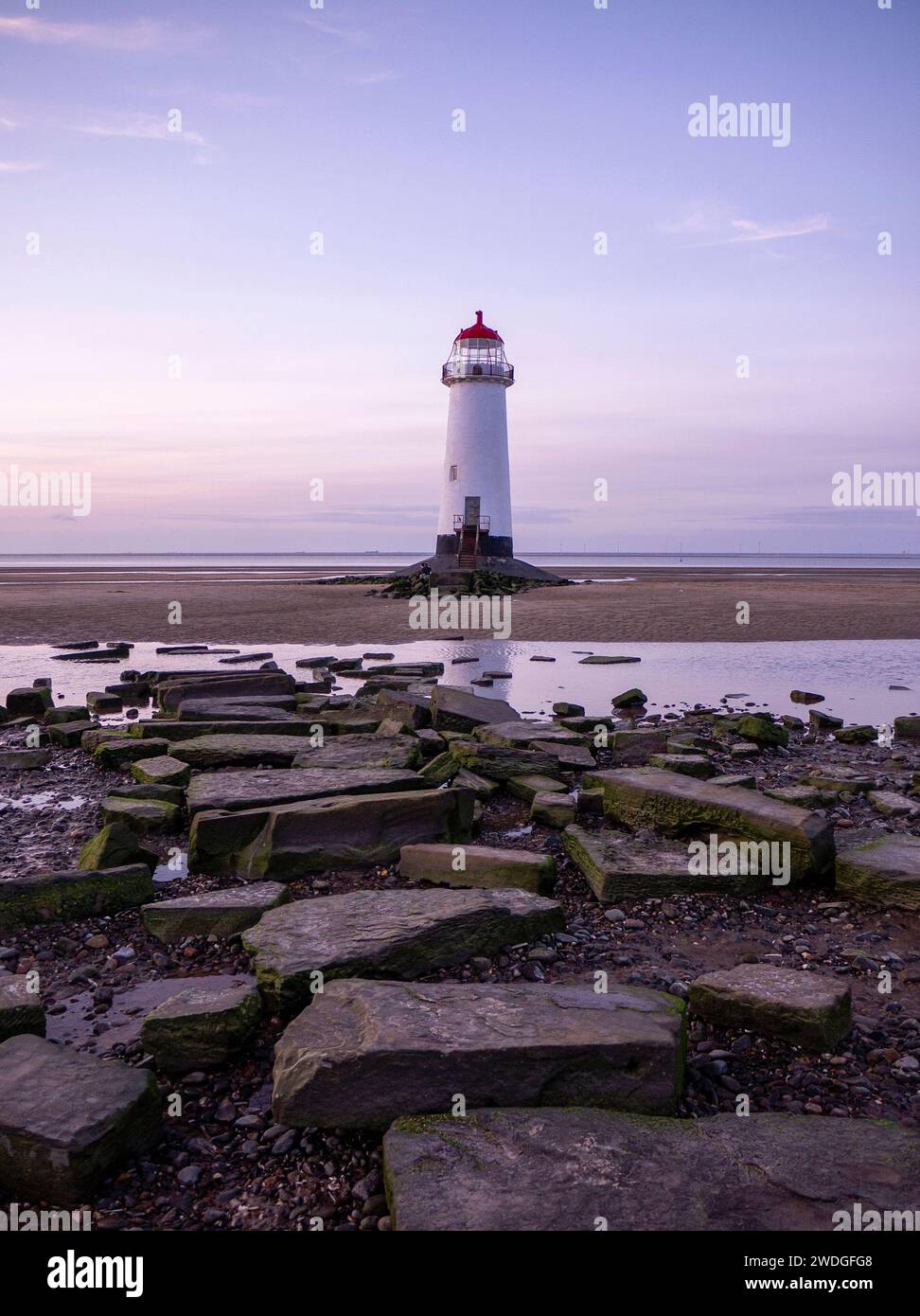 Resti di una vecchia strada rialzata in rovina che conduce al faro di Point Ayr sulla spiaggia di Talacre al tramonto con la bassa marea, Talacre, Flintshire, Galles Foto Stock