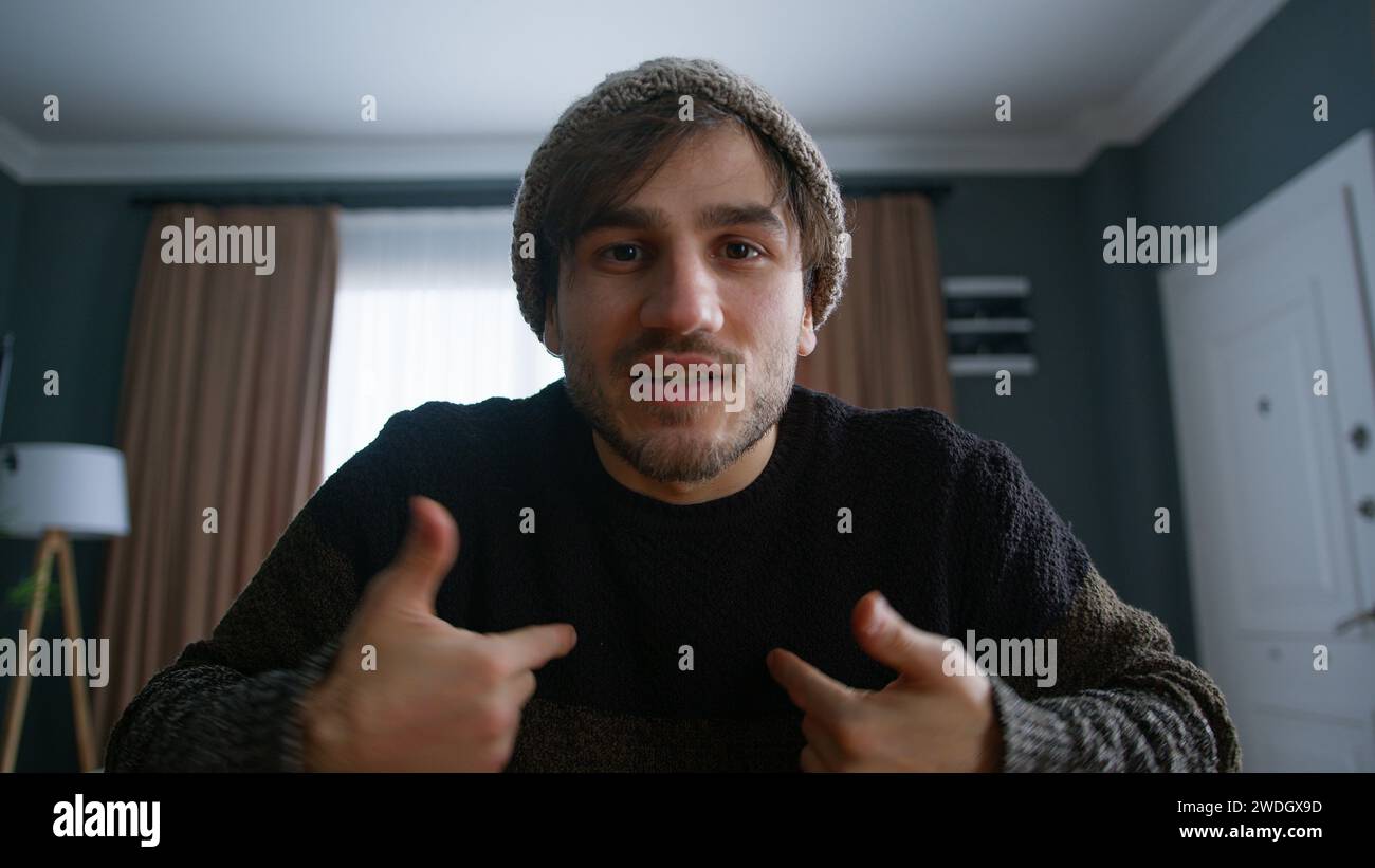 Bell'uomo con un beanie vlogger che fa videochiamate online, registra il blog vlog che parla con la fotocamera guardando la webcam a casa. Videoclip e social media Foto Stock