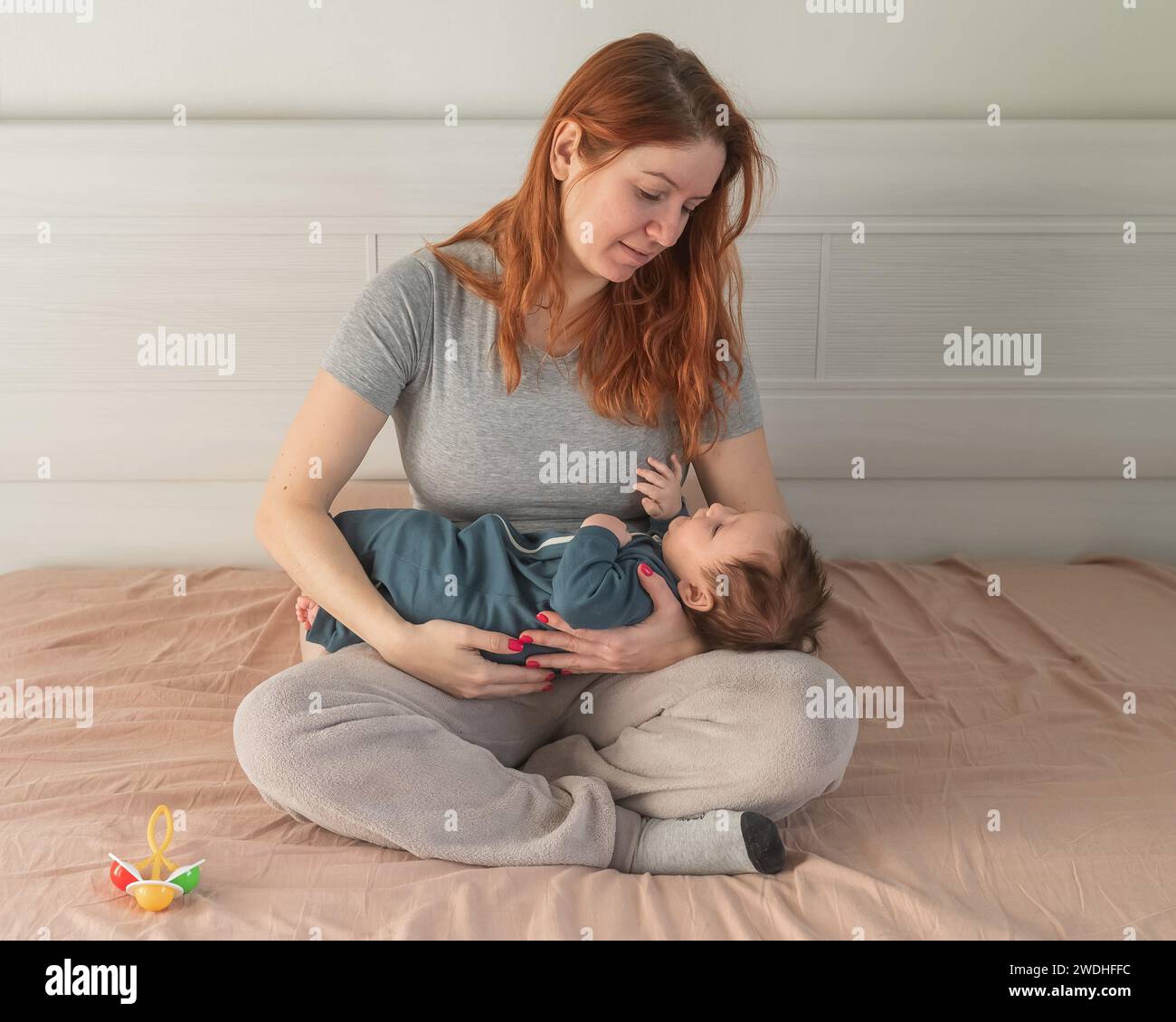 Donna con depressione post-partum seduta sul letto e in attesa di un figlio neonato. Foto Stock