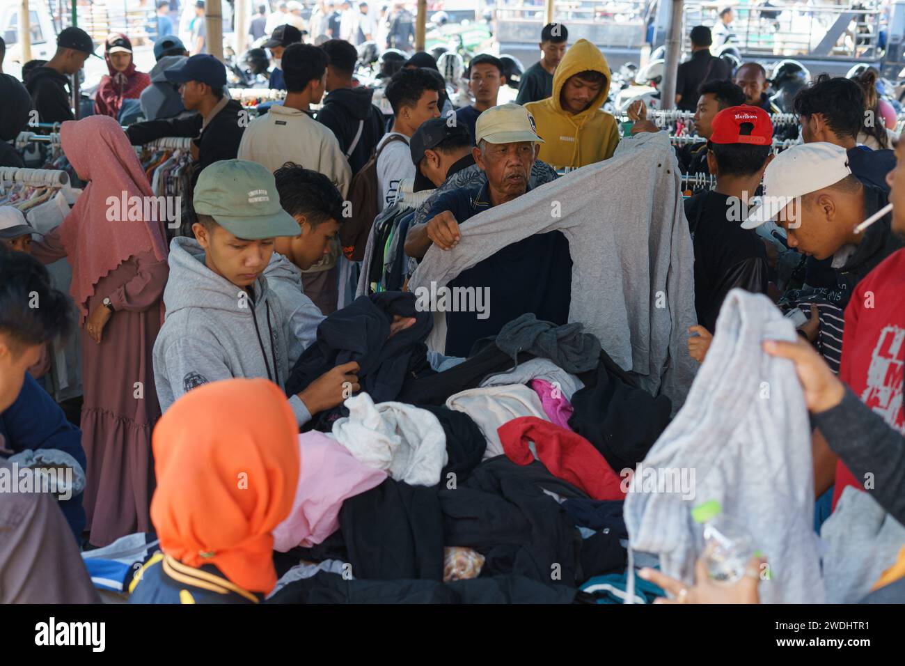 I residenti selezionano e acquistano vestiti di seconda mano in un negozio di articoli di lusso al mercato tradizionale di Pasar Pon a Semarang, Indonesia - 18 dicembre 2023. Foto Stock