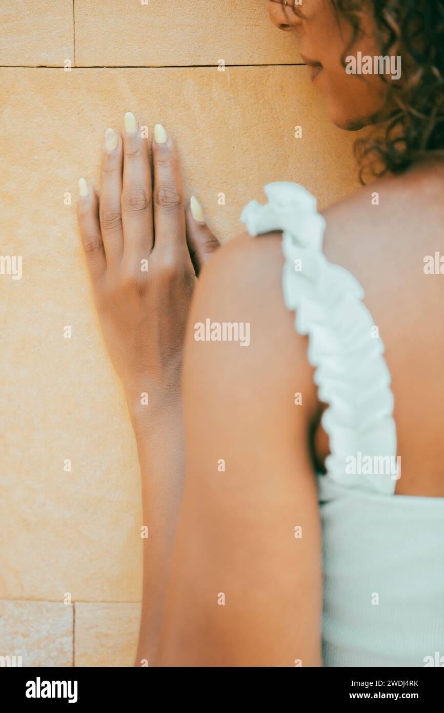 Vista posteriore di una donna appoggiata al muro all'esterno Foto Stock