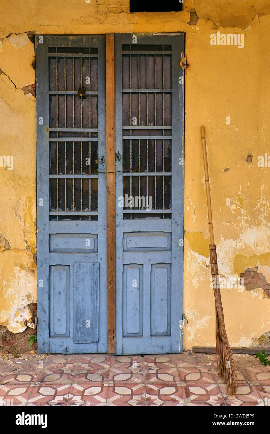 Porta rustica blu sulla parete gialla, vibrante bellezza del vecchio edificio abbandonato. Fotografia minimalista simmetrica Foto Stock