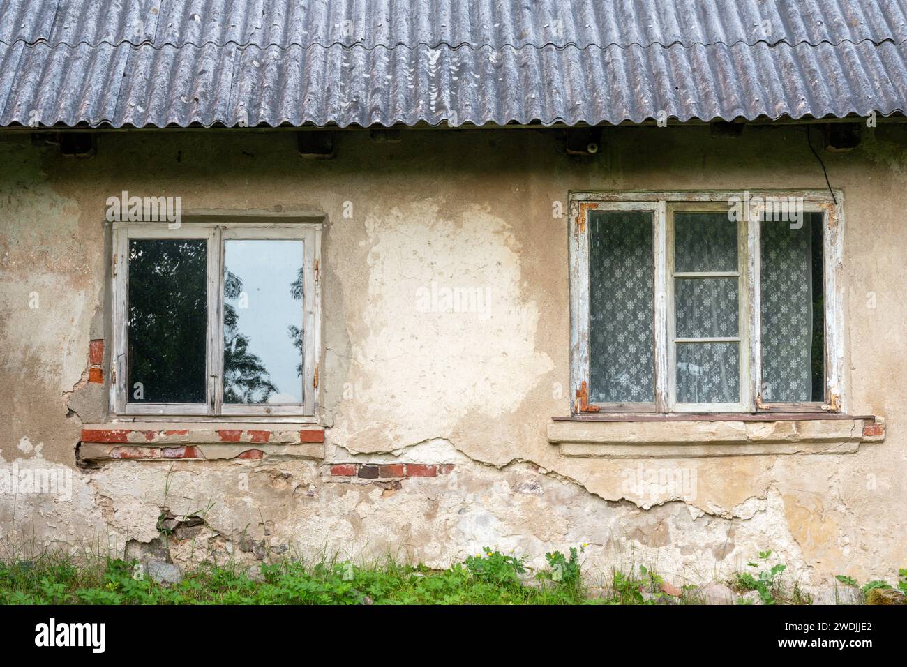 Muro di mattoni di una vecchia casa di campagna con due finestre di legno Foto Stock