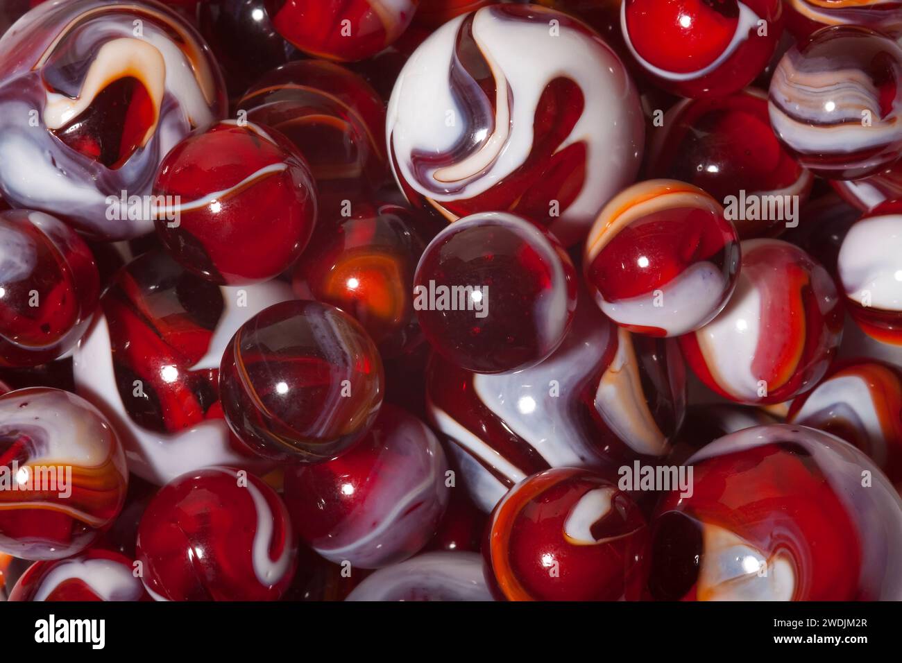 Una collezione di biglie di vetro a vortice rosse e bianche. Foto Stock