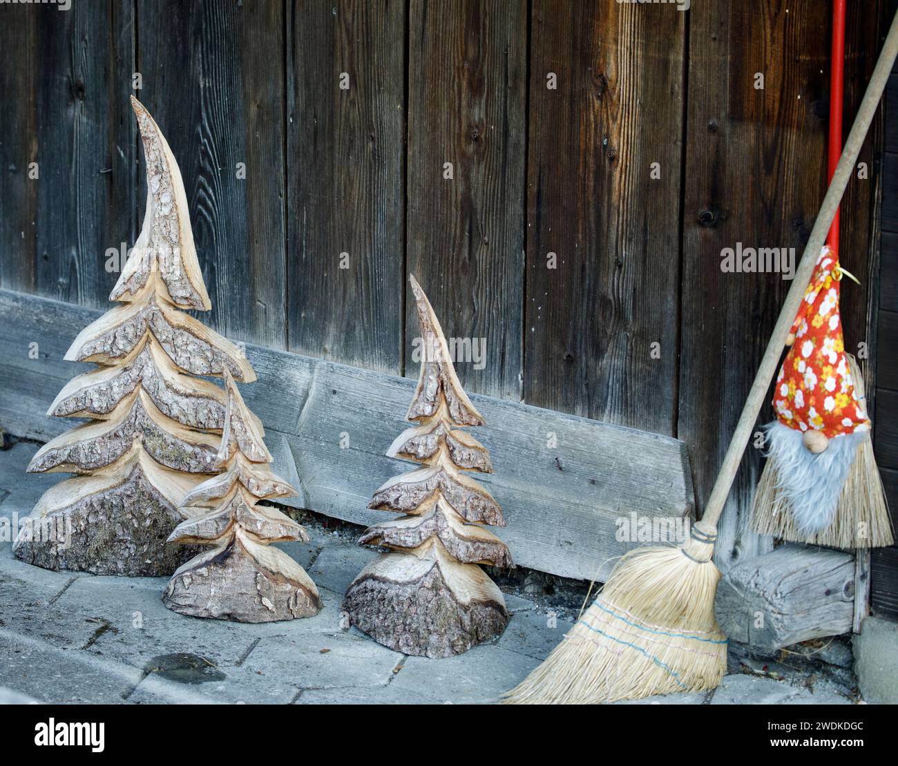 Alberi di Natale scolpiti in legno, una scopa trasformata in un mago e una scopa fuori da uno chalet tradizionale a Grindelwald in Svizzera Foto Stock