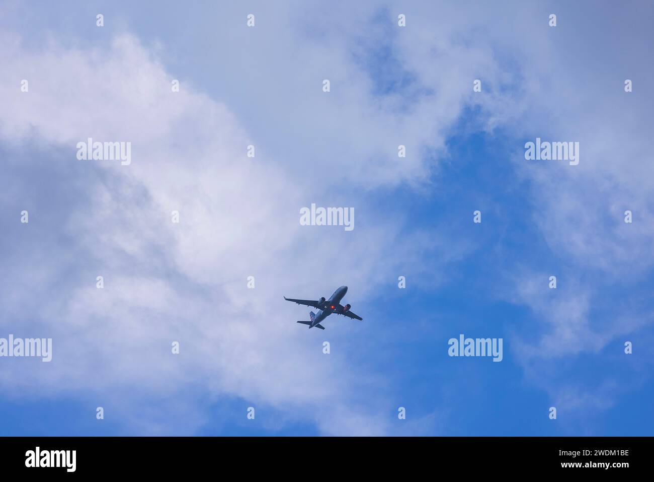 Splendida vista di un aereo da atterraggio con luci accese sullo sfondo di un cielo blu con nuvole bianche. USA. Foto Stock