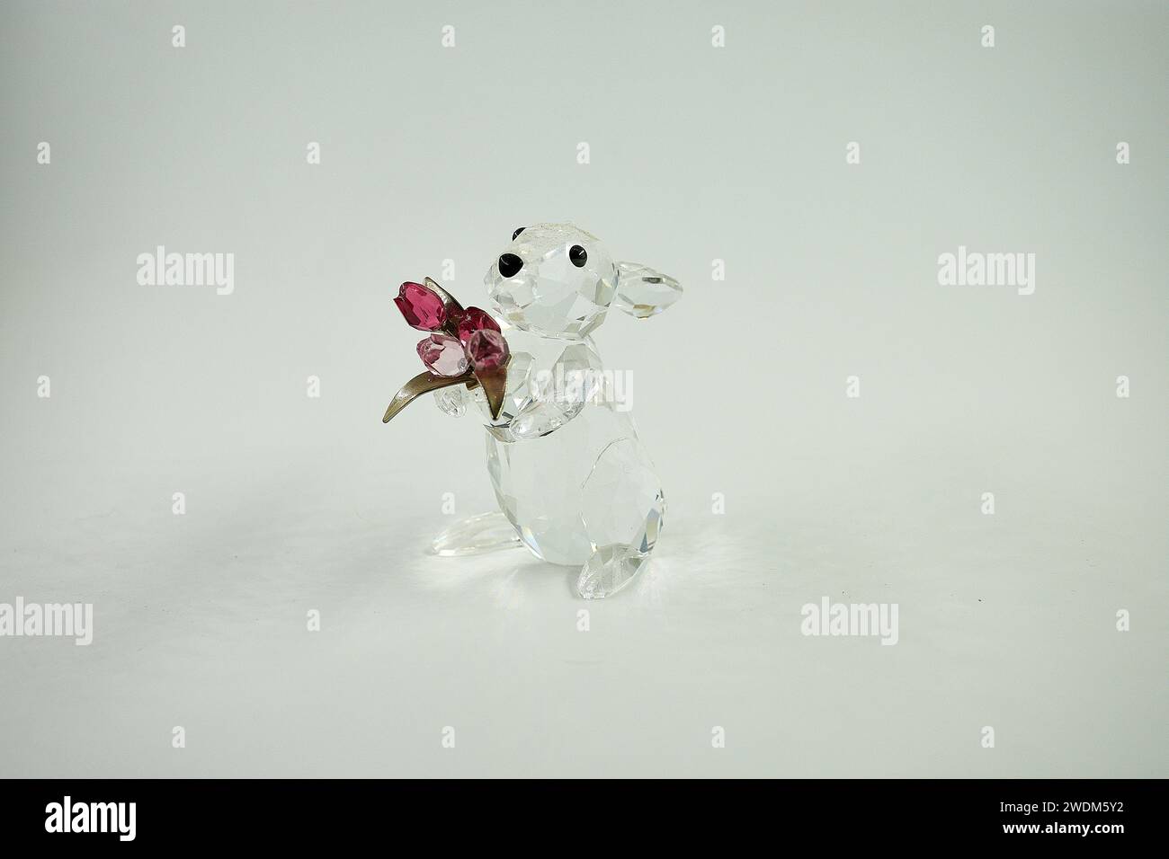 Questo adorabile coniglietto in vetro trasparente contiene un bouquet di tulipani in vetro rosa indiano e rosa chiaro con steli in metallo tonalità argento. Foto Stock