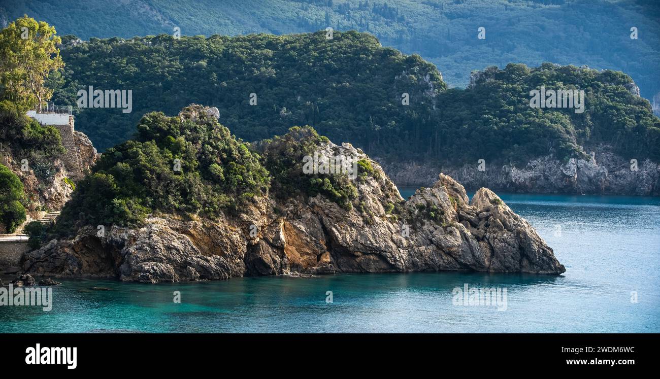 Vista panoramica della costa rocciosa coperta da alberi. Costa rocciosa nell'incredibile blu del Mar Ionio nell'isola di Corfù in Grecia. Foto Stock