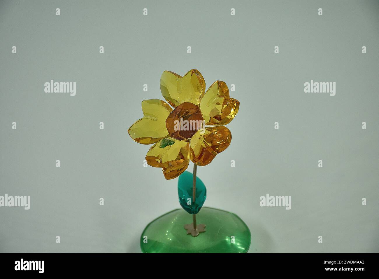 girasole in vetro che oscilla avanti e indietro su uno stelo in metallo argentato. Blossom presenta 5 petali di cristallo topaz giallo chiaro sfaccettati e un cristallo di rame sfaccettato Foto Stock