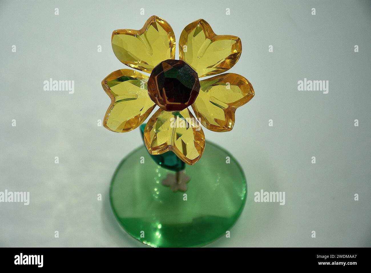 girasole in vetro che oscilla avanti e indietro su uno stelo in metallo argentato. Blossom presenta 5 petali di cristallo topaz giallo chiaro sfaccettati e un cristallo di rame sfaccettato Foto Stock