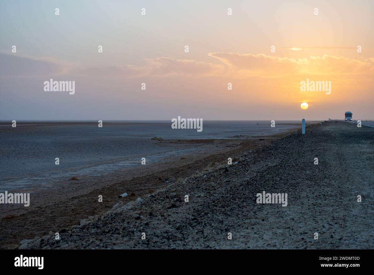Splendido tramonto colorato su infinite strade vuote nel mezzo del deserto. Autostrada asfaltata in Tunisia, Nord Africa. Foto Stock