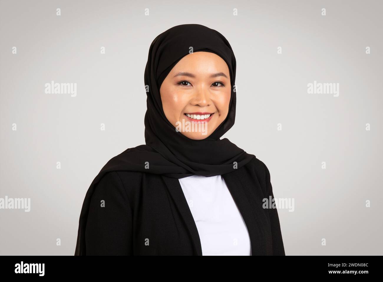 Una radiosa donna d'affari asiatica che indossa un hijab sorride con fiducia Foto Stock