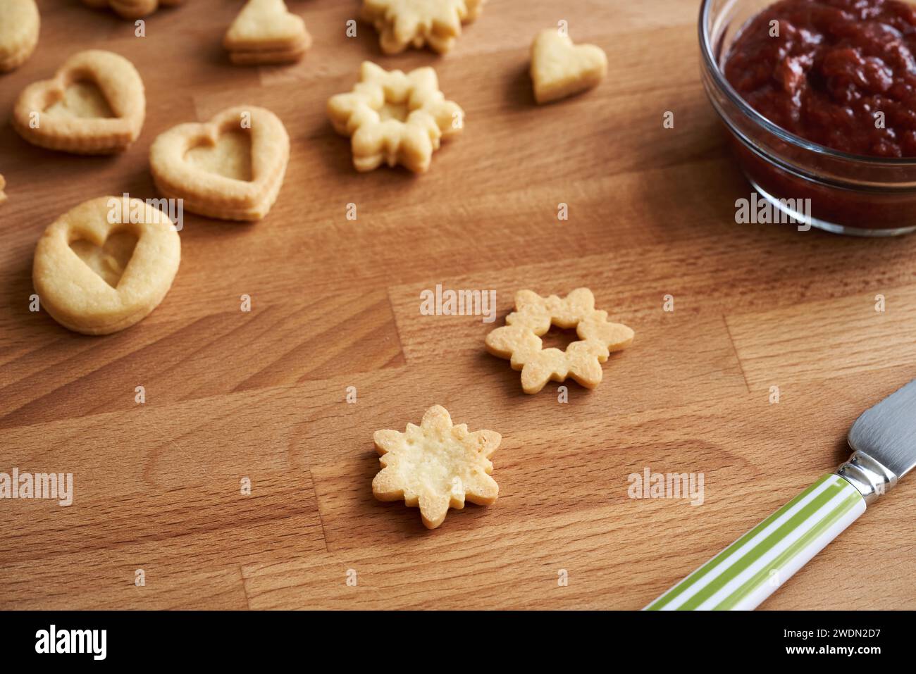 Preparazione di biscotti tradizionali di Natale Linzer - ripieno con marmellata di fragole rosse Foto Stock