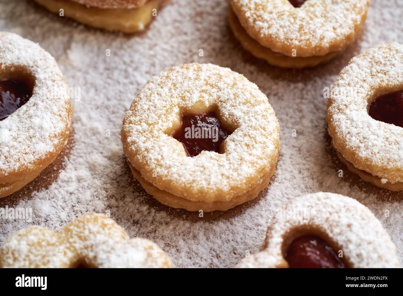 Biscotti di Natale Linzer a forma di cerchio ripieni con marmellata di fragole fatta in casa e spolverati con zucchero Foto Stock