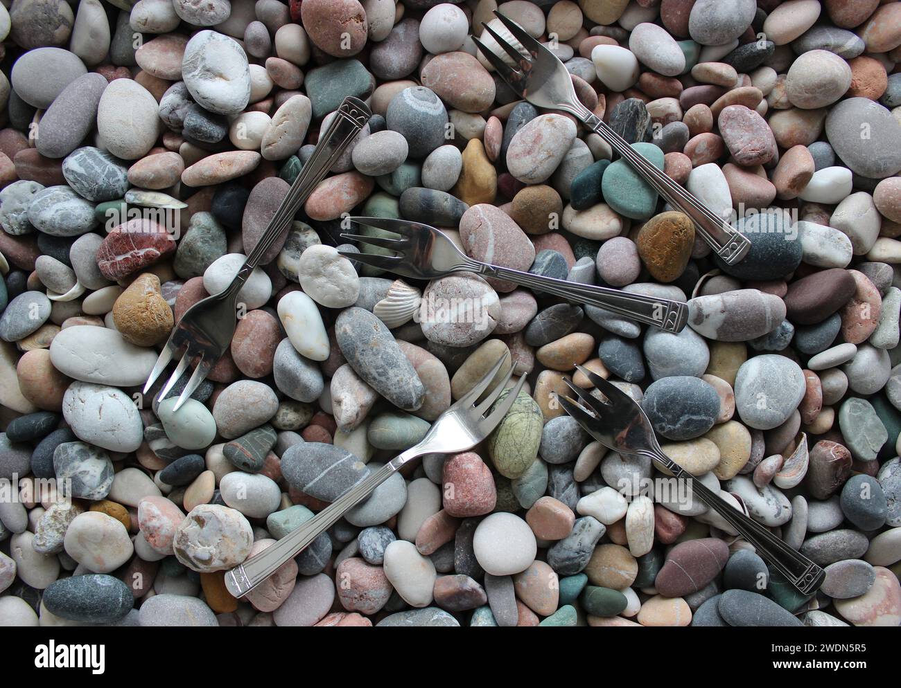 Stesse forche a tre punte sparse sulla foto stock vista dall'alto Smooth Sea Pebbles Foto Stock