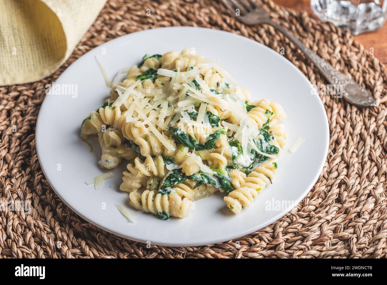 Pasta di fusilli con spinaci e ricotta guarnita con parmigiano grattugiato Formaggio su piatto bianco Foto Stock
