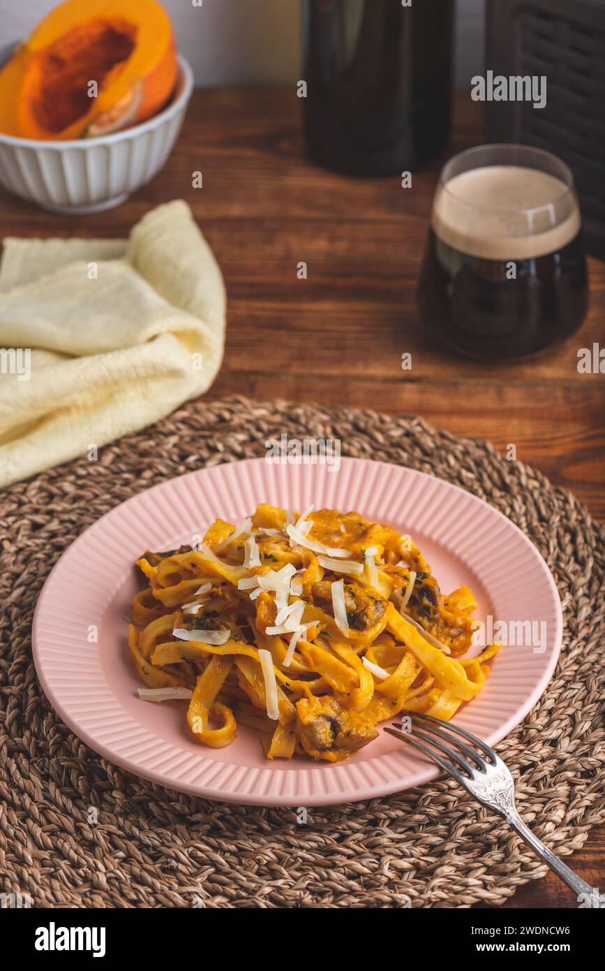 Tagliatelle Pasta con salsa cremosa di zucca e Champignons guarniti con Parmigiano grattugiato Foto Stock