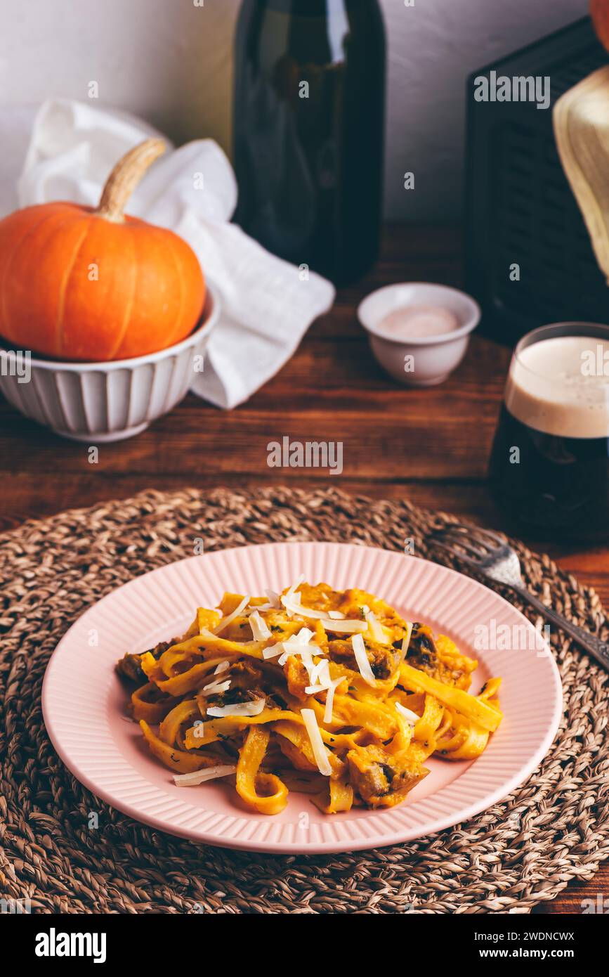 Fettuccine Pasta con zucca e salsa alla panna acida con funghi guarniti con parmigiano grattugiato Foto Stock