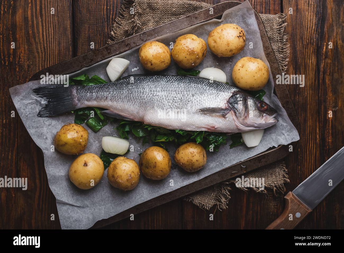 Spigola fresca ripiena di Sorrel su vassoio di cottura pronto per cuocere con patate novelle e cipolle. Vista dall'alto Foto Stock