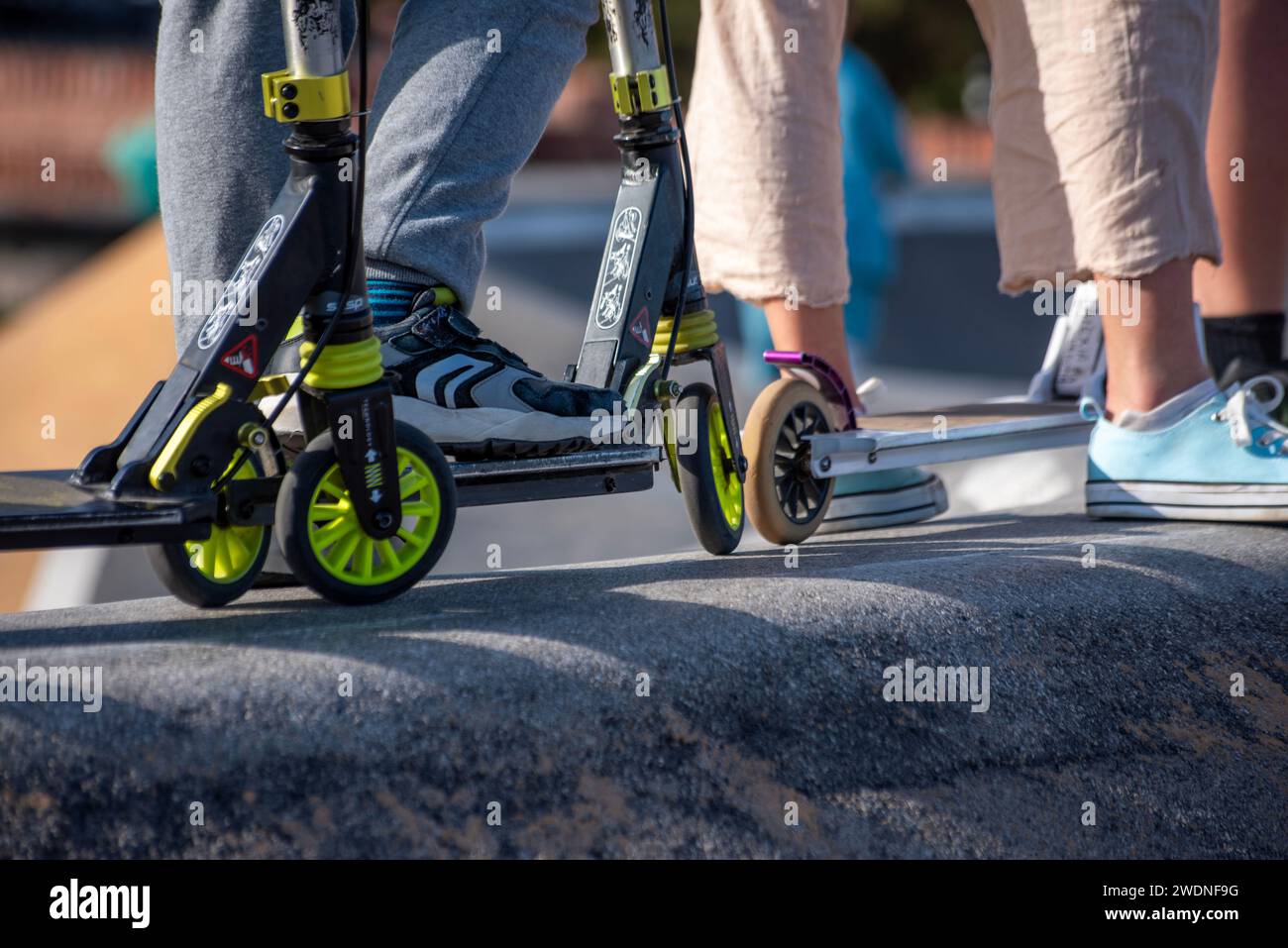 Anticipazione della pista: Piedi e scooter allineati, pronti per un giro dinamico in una coda elettrizzante Foto Stock