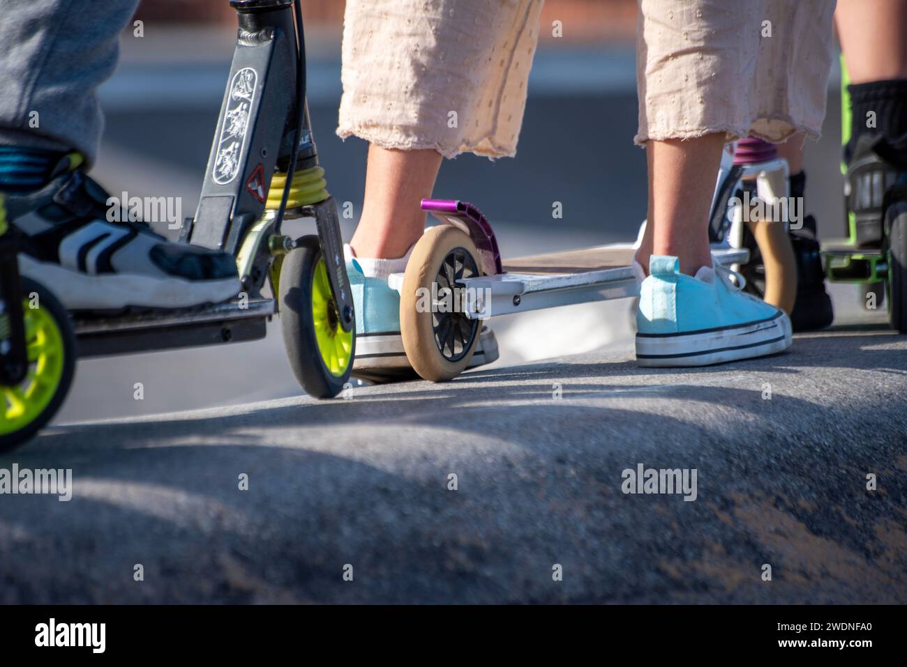 Anticipazione della pista: Piedi e scooter allineati, pronti per un giro dinamico in una coda elettrizzante Foto Stock
