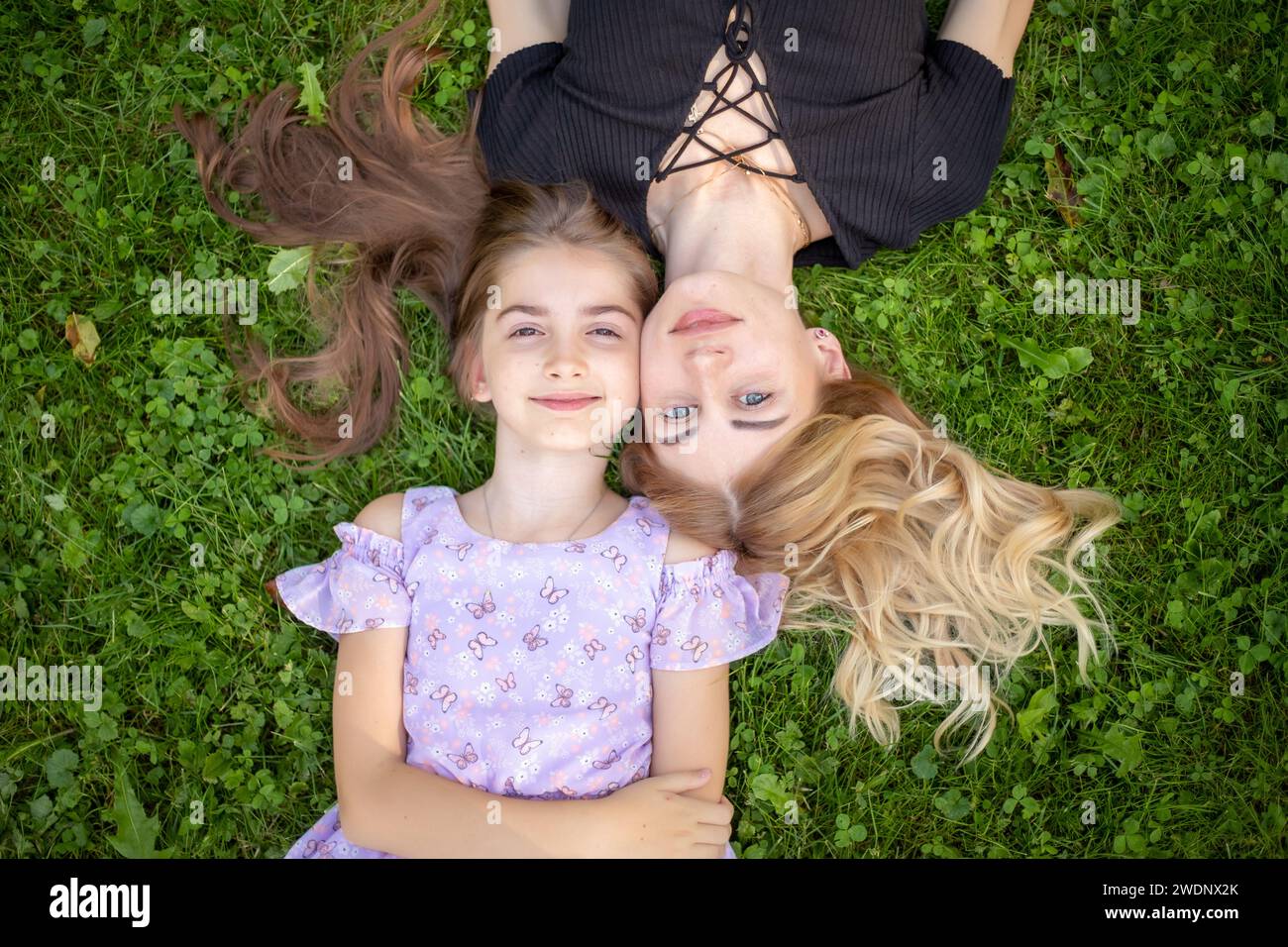 Madre e figlia che abbracciano l'erba. Foto Stock