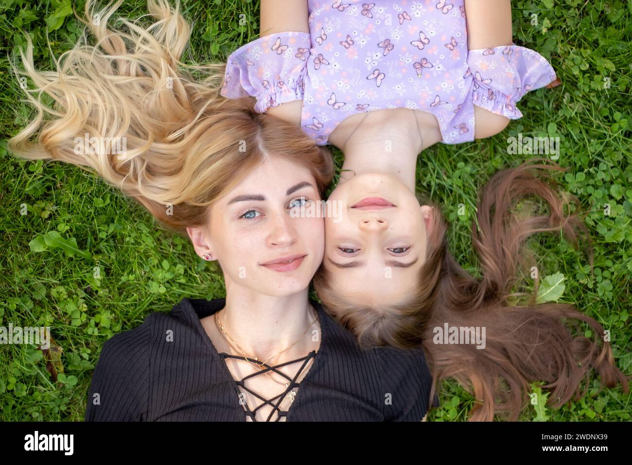 Madre e figlia che abbracciano l'erba. Foto Stock