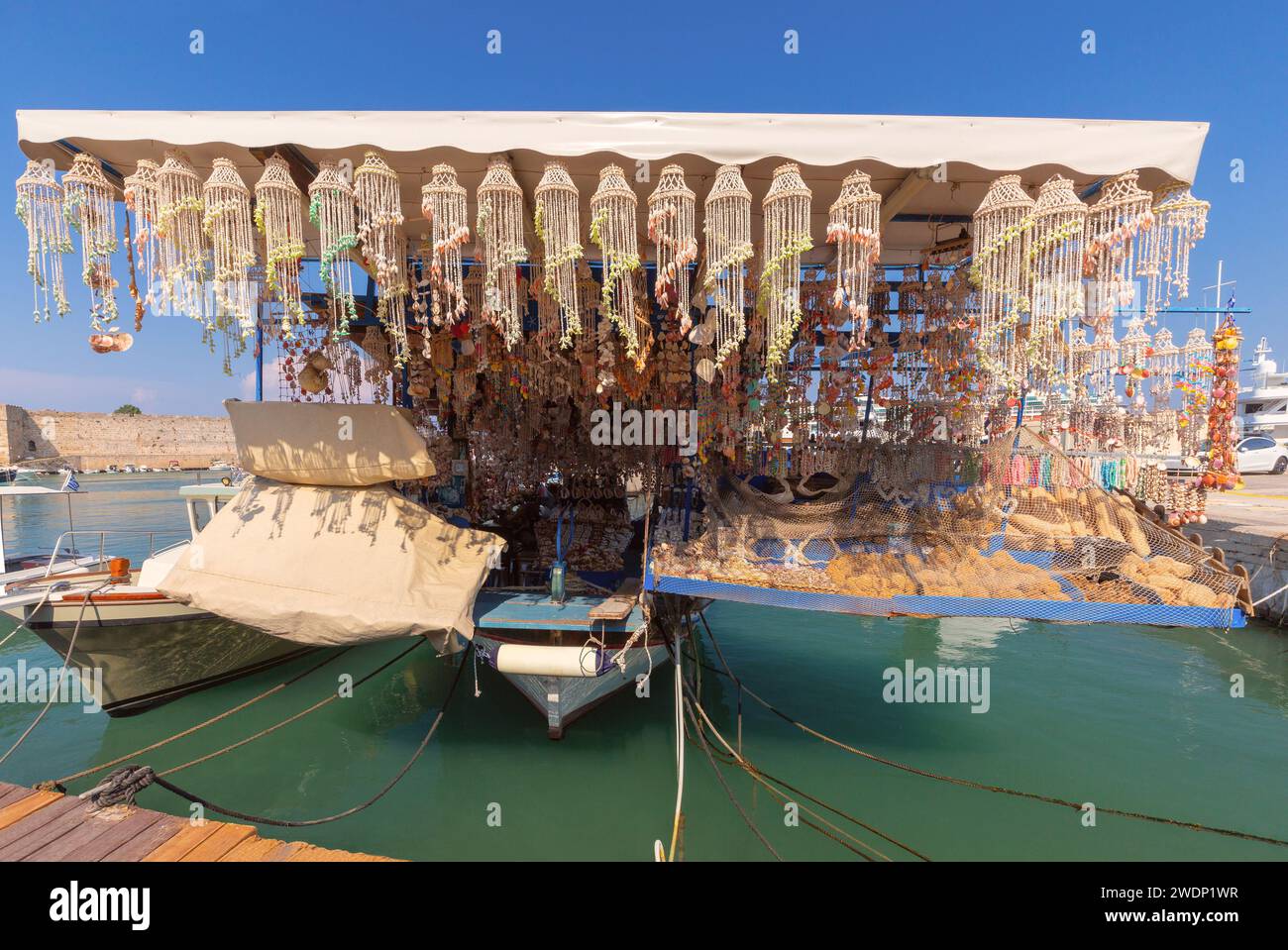 Vista panoramica del vecchio porto di Mandraki con un peschereccio con conchiglie e souvenir in una giornata di sole. Rhodes. Grecia. Foto Stock