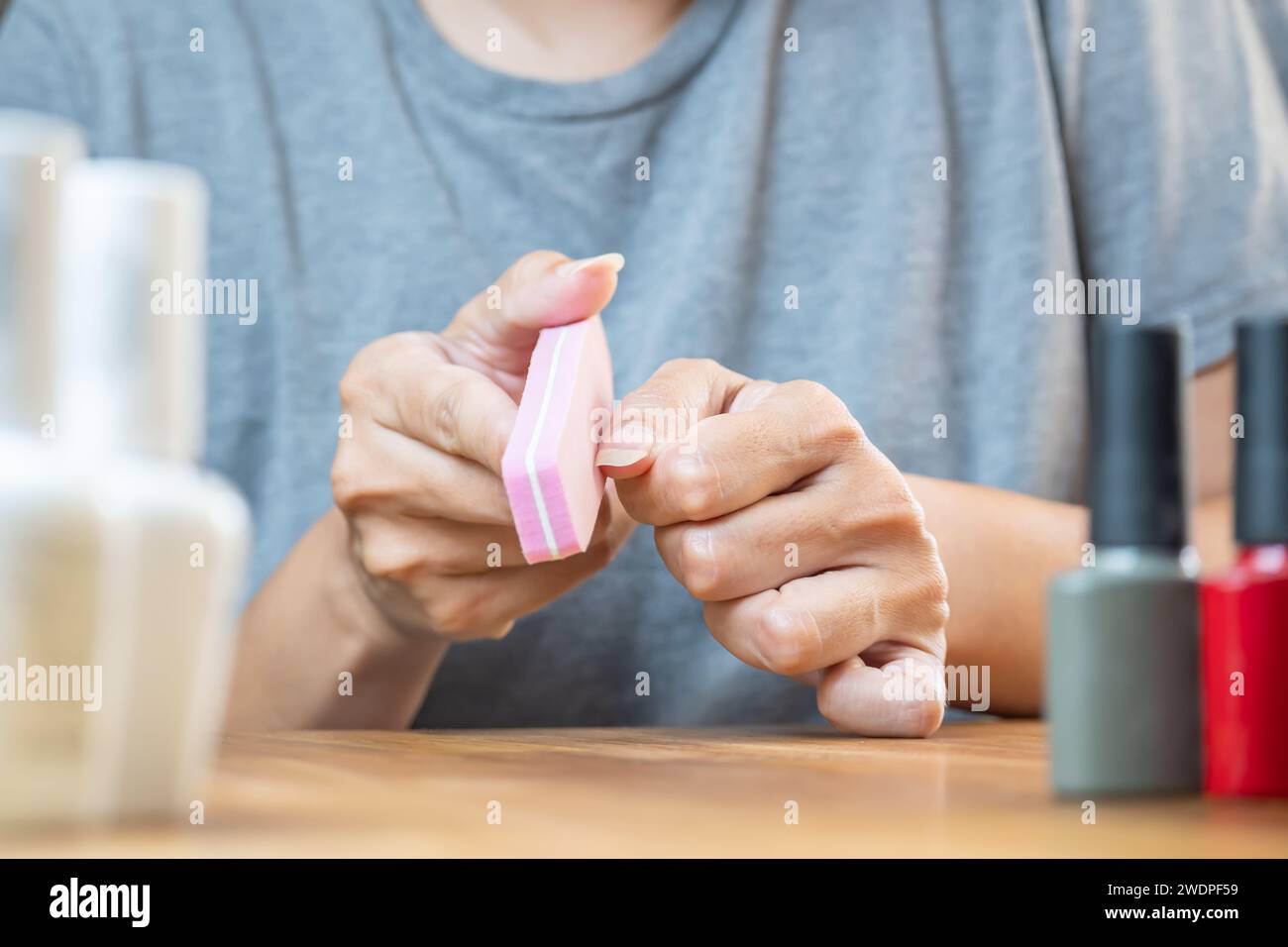 Trattamento manicure. La giovane donna si pulisce le unghie con una lima morbida per migliorare l'aspetto. Foto Stock