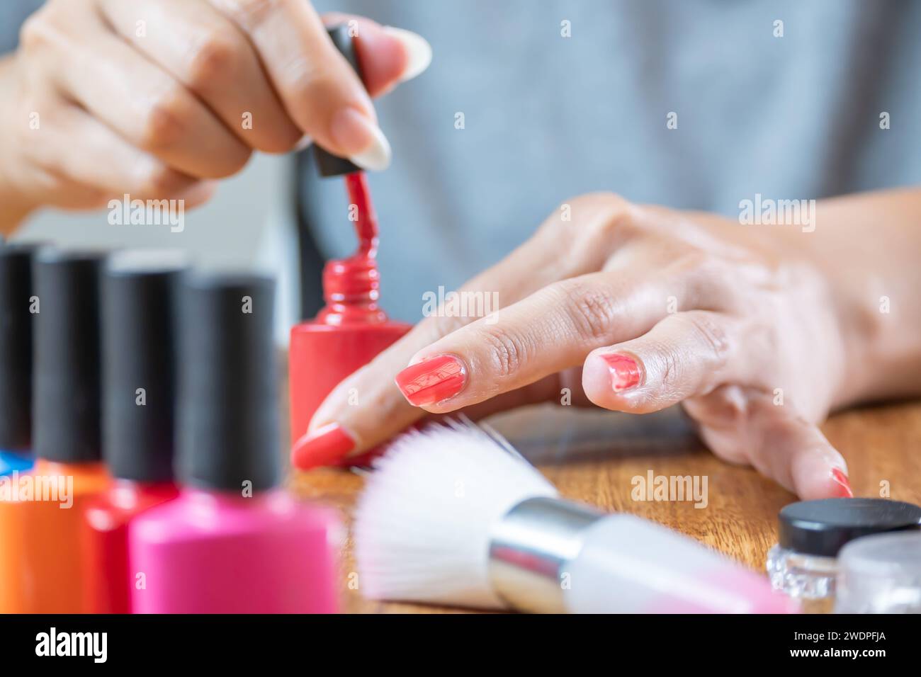 Vernice per chiodi semipermanente rossa. La donna latina lo applica alle sue unghie molto delicatamente. Foto Stock