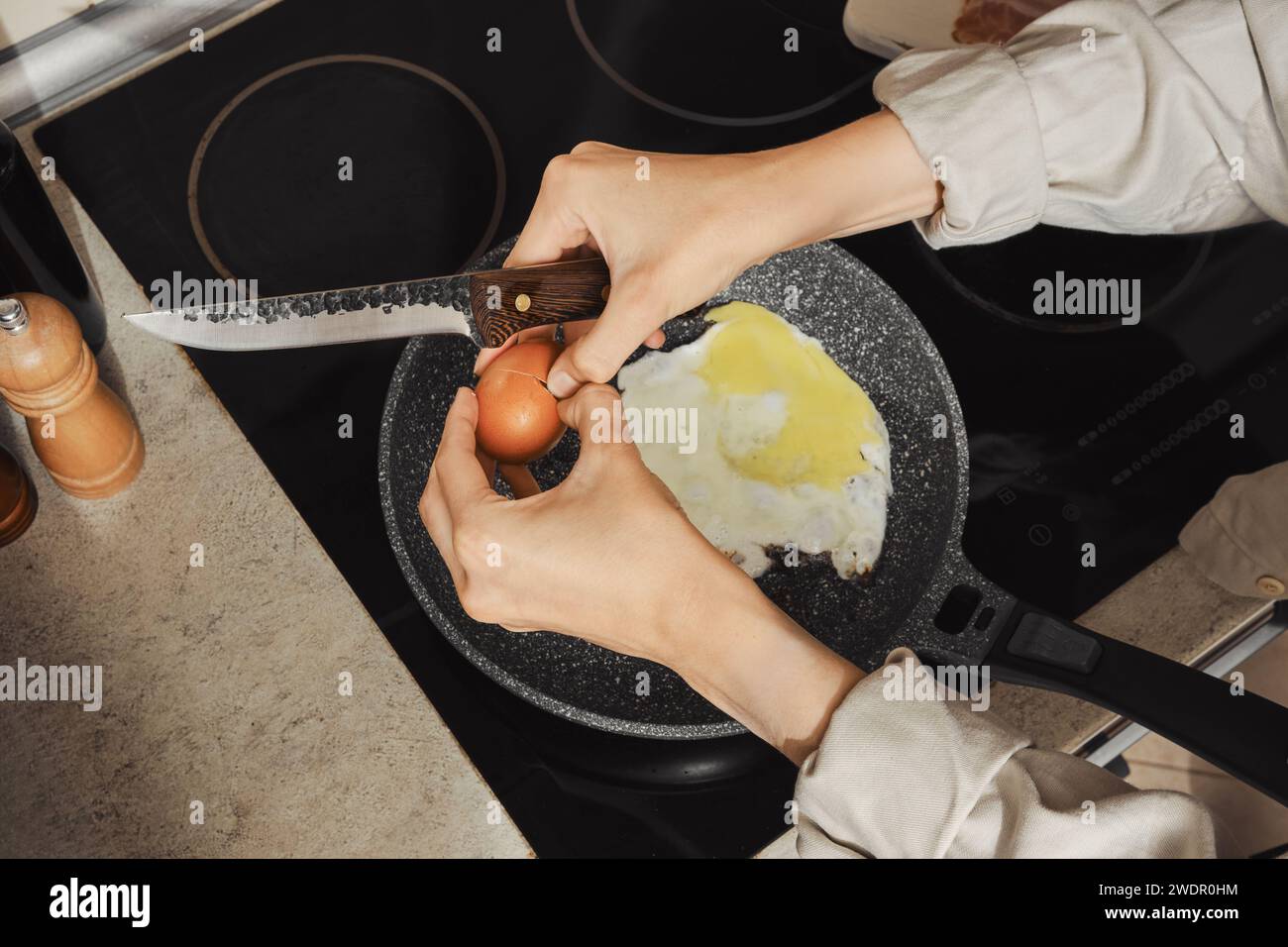 Vista dall'alto di una donna che rompe un uovo in una padella Foto Stock