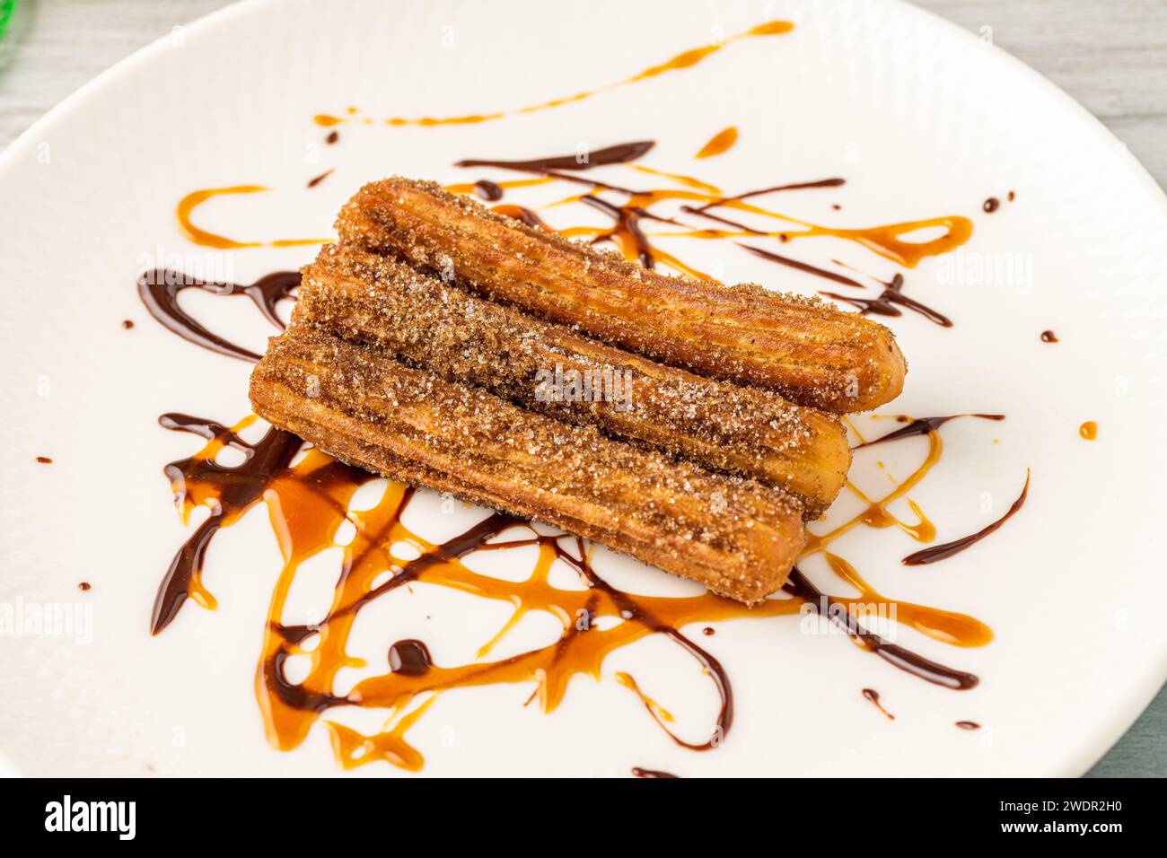 Churros caldi con salsa di cioccolato su tavola di legno. Foto Stock