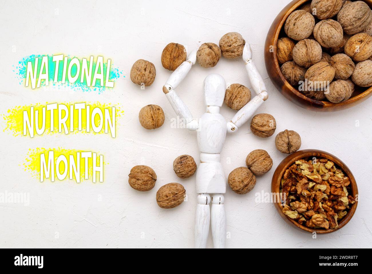 Festeggia il mese nazionale della nutrizione con scelte salutari - Una figura di legno circondata da noci Foto Stock
