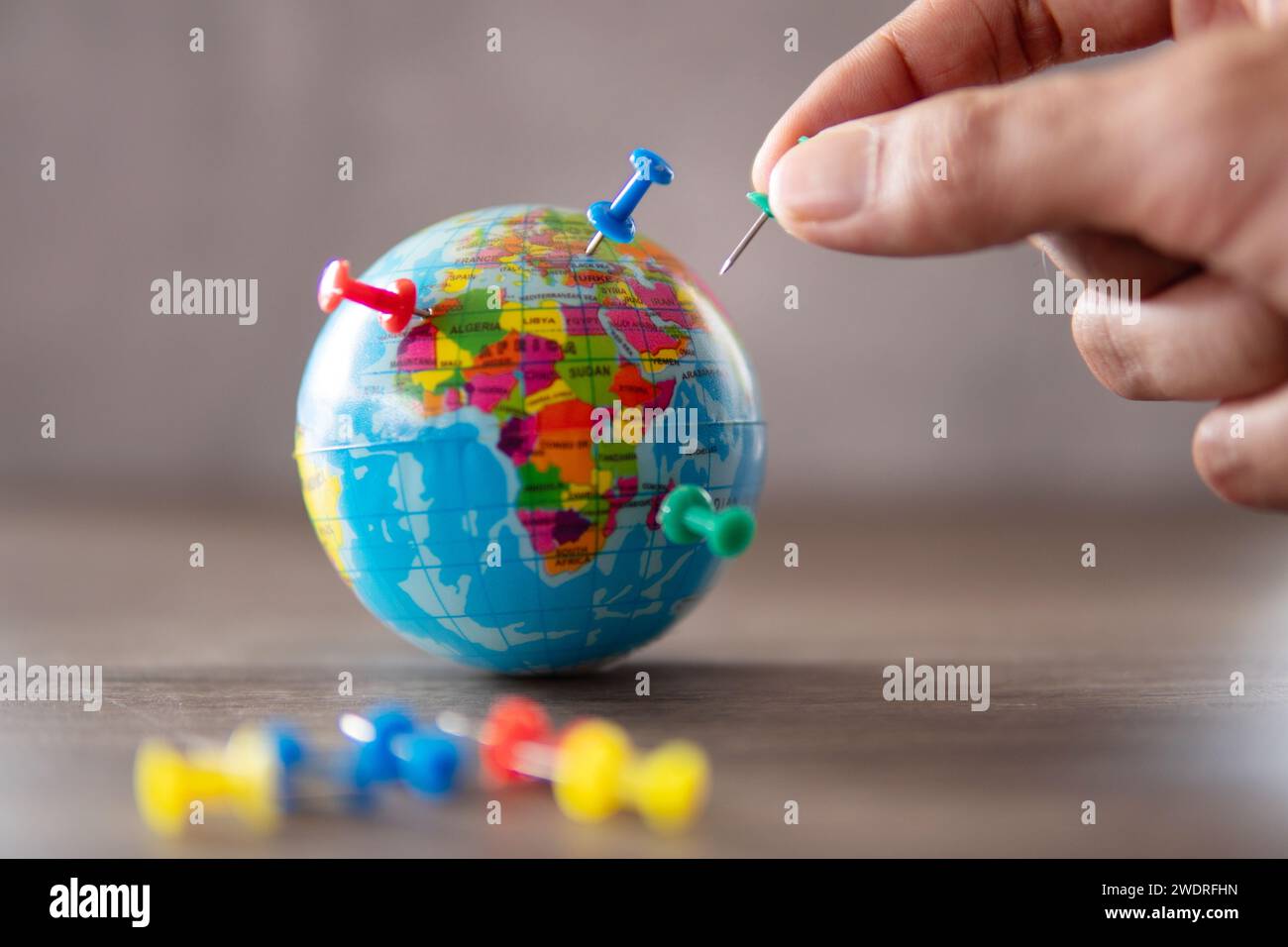 Immagine ravvicinata della mano che mette i perni sul globo mondiale. Destinazione di viaggio, pianificazione del concetto di vacanza. Foto Stock